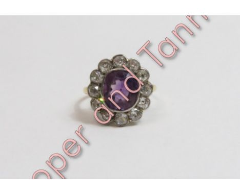 An amethyst and diamond cluster ring, unmarked, the oval cut amethyst enclosed by twelve old brilliant cuts totalling approxi