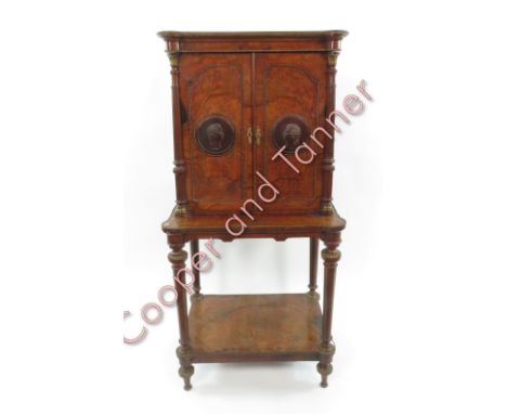 A veneered music cabinet on stand, decorated with metalwork beading and edging; and a pair of rosewood roundels to each door,