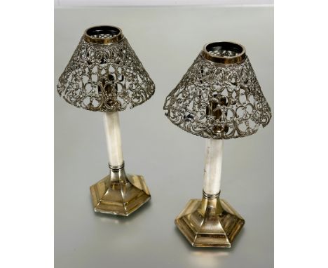 A pair of Edwardian Epns table candle sticks with metal shade holders and white enamel sprung columns raised on octagonal wei
