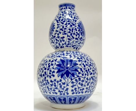 A good Qianlong-style Chinese blue and white porcelain double gourd form vase decorated with scrolling vine and lotus bloom, 