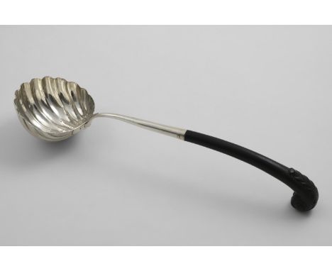 A GEORGE II SOUP LADLE with a fluted circular bowl, a double drop and a carved wooden leaf-capped pistol handle, the bowl cre