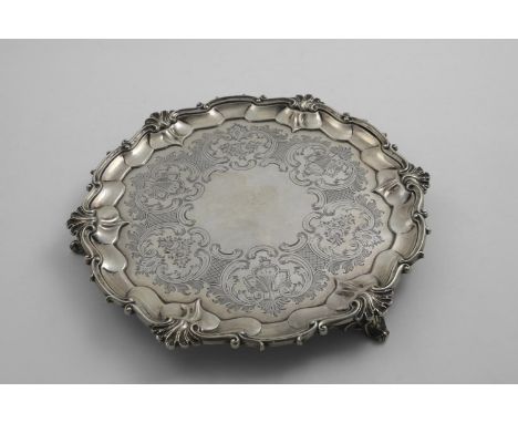 A VICTORIAN ENGRAVED SALVER of shaped circular outline with a husk and scroll border and scroll bracket feet, by Messrs. W &a