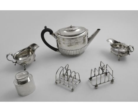 A MIXED LOT:- Two toast racks, a George II chased sauce boat, an early 20th century sauce boat, an Edwardian small oval tea c