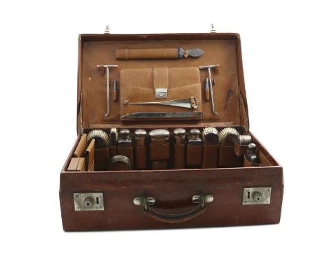 AN EARLY 20TH CENTURY CROCODILE LEATHER DRESSING CASE fitted with the following:- A spirit flask, two toilet water flasks, tw