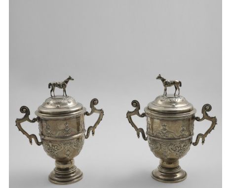 HUNTING:- A matched pair of early 20th century two-handled cups and covers with chased formal decoration, and horse finials, 
