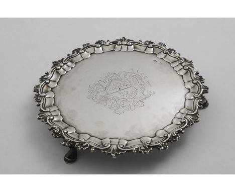 AN 18TH CENTURY SMALL CIRCULAR SALVER with a husk and scroll border, engraved in the centre with a lozenge-shaped coat of arm