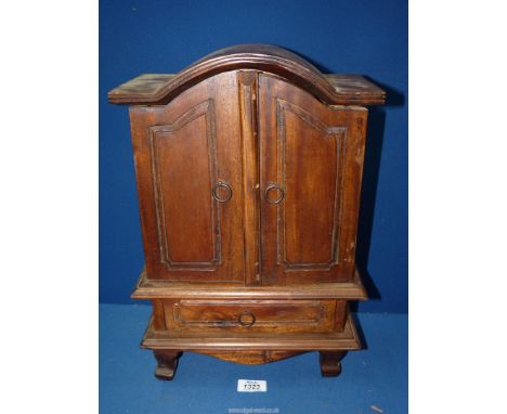 A compact Eastern hardwood Cabinet, the fielded opposing doors opening to reveal an interior with three drawers and with a lo