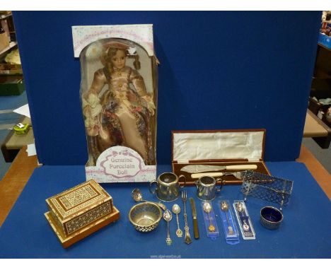 A porcelain doll, a serving knife and fork, a wooden musical cigarette box, souvenir spoons, sugar bowl and jugs etc.