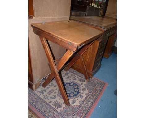 An unusual Oak folding School Desk having open trough and an inkwell recess, 24" wide x 17 3/4" deep x 29 7/8" high approx.