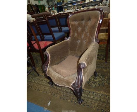 A Victorian Mahogany show framed button back Armchair, upholstered in brown cord fabric and standing on scroll front legs.