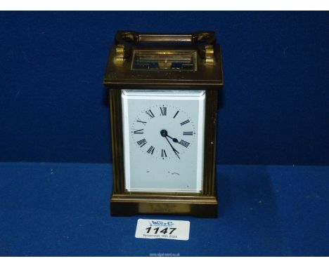 A brass and bevelled glass cased Carriage Clock the enamelled face having Roman numerals, the escapement wheel of the Swiss m