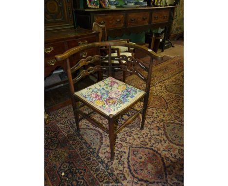 An arts and crafts type of Corner Elbow Chair having turned supports, fretworked cross splats and a tapestry upholstered seat