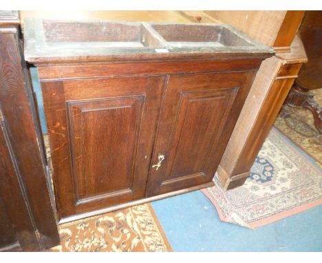 A dark Oak Cupboard having a pair of opposing raised and fielded panelled doors revealing an interior with fourteen pigeon ho