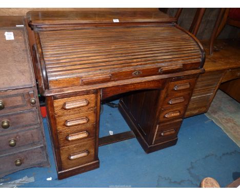 An unusually compact Oak double pedestal "The Lebus" roll top Desk, the interior with six drawers and six recesses, the kneeh