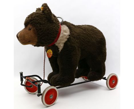 Reitbär, Steiff. Brauner Mohair. Mit K, F und S. Metallgestell auf Rollen. Gebrauchsspuren, angeschmutzt. L. 63 cm.