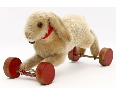 Hase auf Exzenterrädern, Steiff. Blonder Mohair (teils etwas abgeliebt), fester Kopf mit braunen Glasaugen, rote Schleife mit