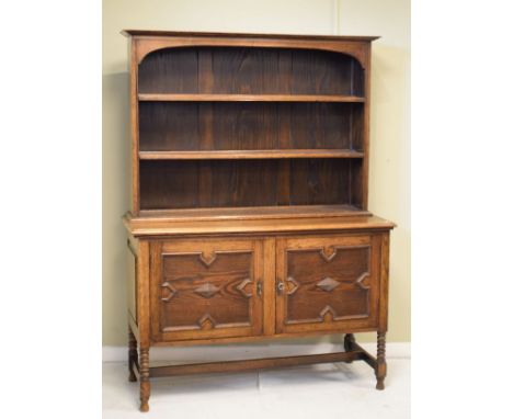 1920's period oak Jacobean Revival dresser, the upper section fitted three shelves, the base fitted two cupboard doors and st