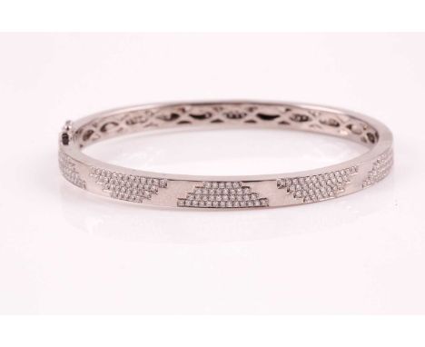 An 18ct white gold and diamond bracelet; the polished bangle with pave set round brilliant cut diamond panels; concealed clas