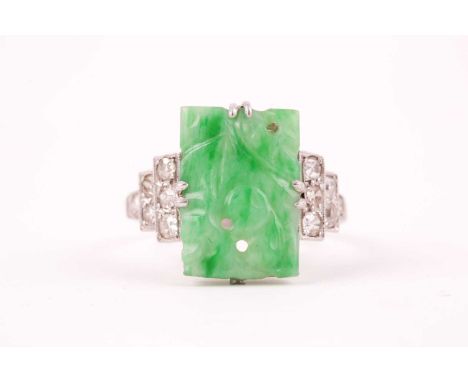 An early 20th century 18ct white gold, diamond, and jade ring, set with a pierced and carved rectangular jade plaque, the ste