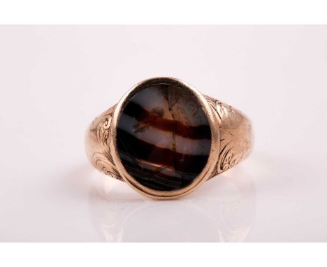 A 19th century agate signet ring; the oval banded agate plaque with intaglio crest engraving; tapering foliate engraved shoul