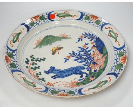* * An 18th century delftware dish, the centre painted with a wolf, a bee and a pavilion, 35cm Please note this lot attracts 