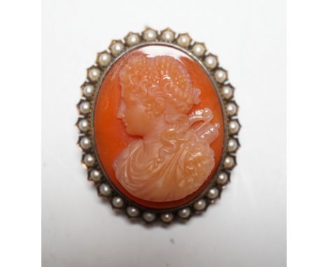 A Victorian yellow metal, and seed pearl mounted oval hardstone cameo pendant brooch, carved with the bust of a lady to dexte