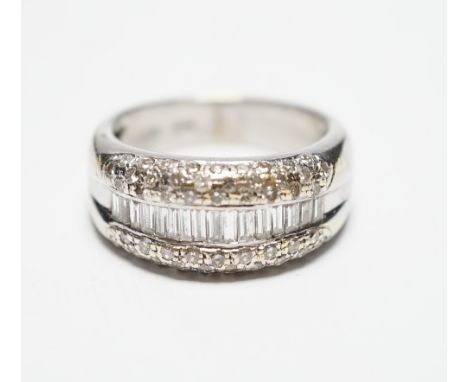 A modern 750 white metal and graduated baguette cut diamond set half hoop ring, with diamond chip set borders, size N, gross 