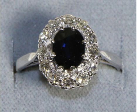 A Sapphire and Diamond Cluster Ring, an oval cut sapphire within a border of eight-cut diamonds in claw settings, to angular 