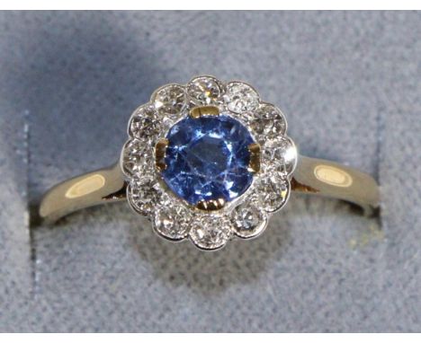 A Sapphire and Diamond Cluster Ring, a round cut sapphire within a border of eight-cut diamonds, to knife edge shoulders, tot