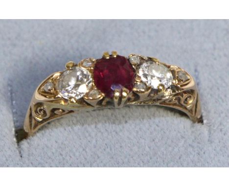 An 18 Carat Gold Ruby and Diamond Three Stone Ring, an oval cut ruby between two old cut diamonds in a carved setting, total 