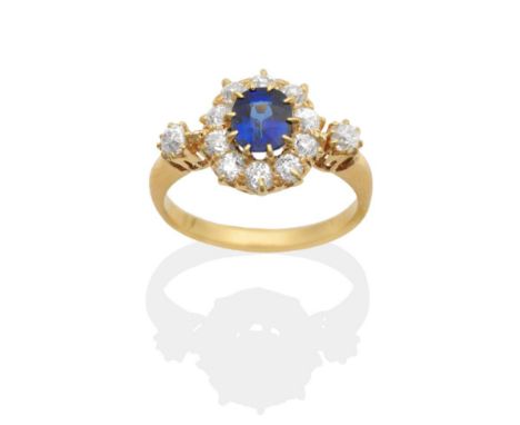 A Sapphire and Diamond Cluster Ring, an oval cut sapphire in a claw setting within a border of old cut diamonds, to diamond s