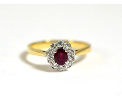 A Ruby and Diamond Cluster Ring, a round cut ruby in a claw setting, within a border of round brilliant cut diamonds in milgr