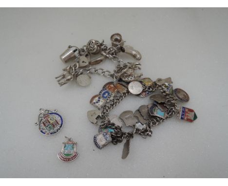 An HM silver charm bracelet having padlock clasp and eleven white metal and HM silver charms, another similar HM silver charm