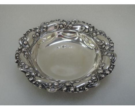 An American white metal trinket dish stamped Sterling of circular form having Lily of the Valley repousse decoration,  R Wall