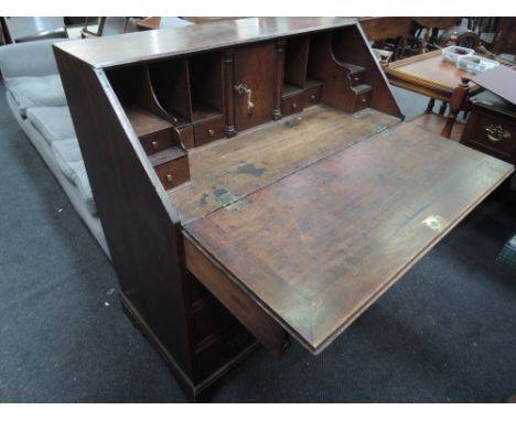 An early 19th century oak bureau of traditional design on drawer base and bracket feet and a similar period cut down vernacul