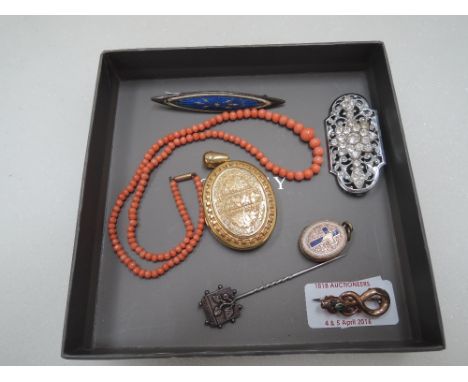 A small selection of costume jewellery including a Victorian yellow metal locket having extensive engraved decoration, string