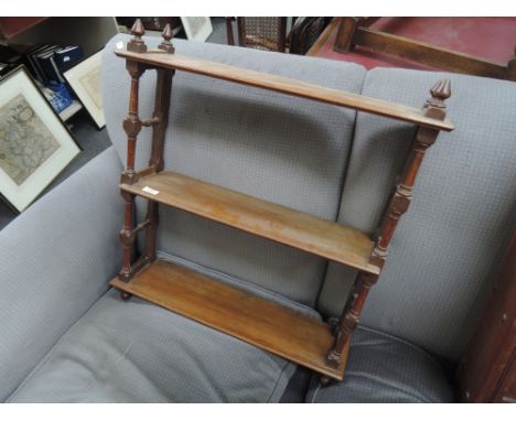 An early 20th century golden oak wall shelf having turned supports