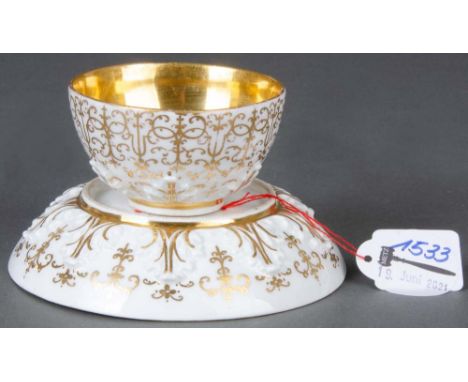 Koppchen mit Unterschale. Meissen 1725-30. Beide Teile mit reliefiertem Akanthusfries und breiten Goldspitzenbordüren. Innenw