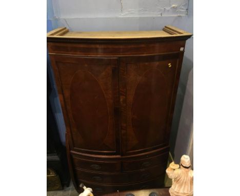 A reproduction mahogany bow front cabinet, with adjustable shelves, below a brushing slide and two short and two long graduat