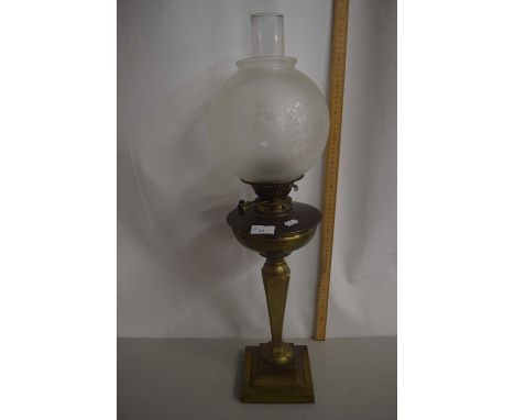 A brass oil lamp with frosted glass shade