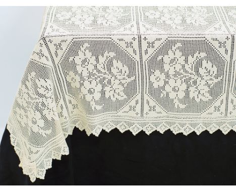 An old hand crocheted tablecloth, beige with a square pattern filled with a bouquet of flowers and large frill measuring 300x