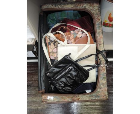 A tapestry suitcase containing nine vintage skirts in a variety of styles including two kilts, and four vintage handbags