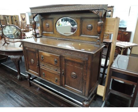 A 1920's oak sideboard having raised pillar mirror back over central drawers flanked by cupboards on melon supports