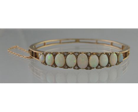 VICTORAN OPAL AND DIAMOND HINGED BANGLE of nine oval opals graduated to the centre with diamond points between.  Weight 14.7g