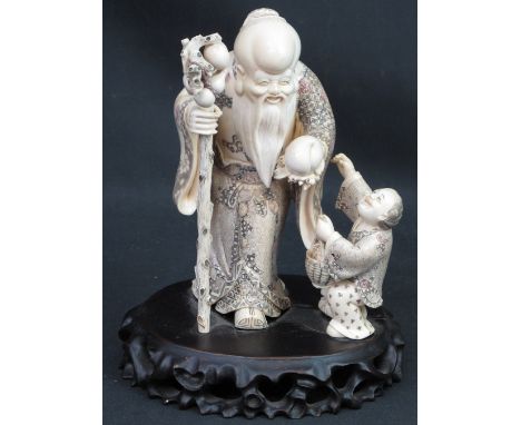 A JAPANESE CARVED IVORY GROUP depicting a bearded immortal figure with gnarled stick, holding a gourd, with a young boy with 