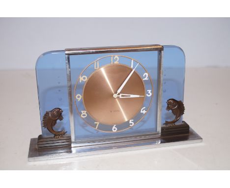 An Art Deco cut glass and chromium plate timepiece, the base mounted with stylised fish, c.1930. The clock with an 8 day move