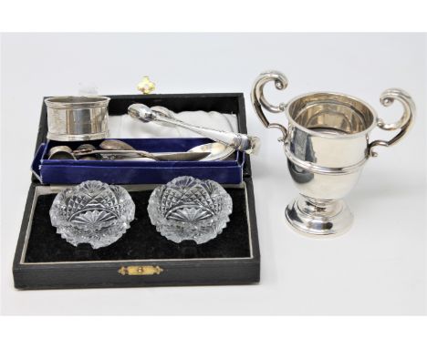 A miniature silver trophy, silver sugar tongs and other flatware, napkin ring and a cased pair of cut glass salts (Qty)