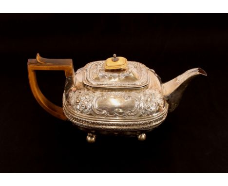 A George III silver teapot, having raised foliate embossed decoration and vacant cartouche, ivory handle and lift, on ball fe