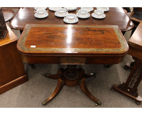 A Regency rosewood and brass inlaid card table, with foldover swivel top, raised on a turned baluster column, quadruple splay