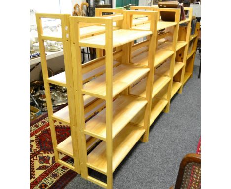 Six modern pine floor standing folding four shelf units; a three shelf pine bookcase